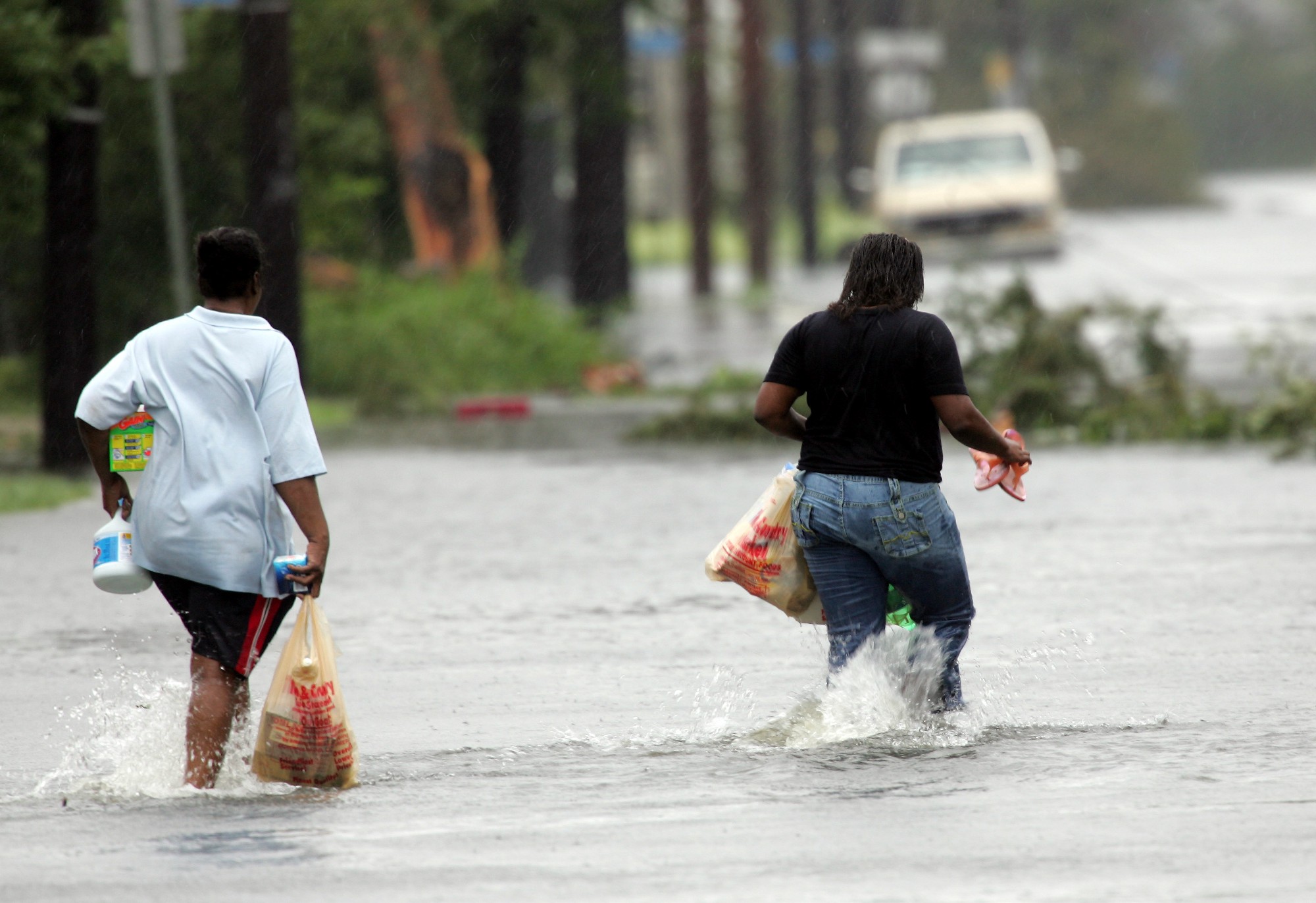 People carry bags of groceries through floodwaters after taking the merchandise away from a wind damaged convenience store in New Orleans on Monday, Aug. 29, 2005. (AP Photo/Dave Martin)